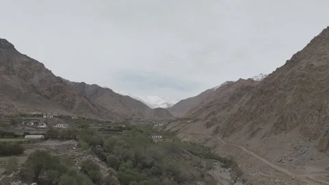 Drone Pull Out Over Ladakh Village Green Fields with Snow Mountain Valley with Stock-Footage 335751122