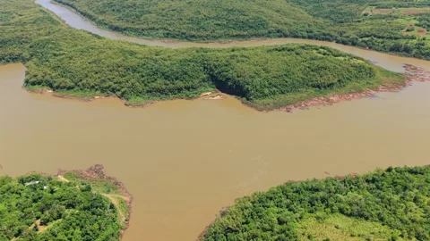 Drone pull out over Paraná River winding through green forest landscape in Stock Footage 327463514