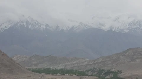 Drone Pull Out Revealing Snow Covered Ladakh Mountain Valley with Green Forest Stock-Footage 335760488