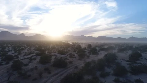 Drone pull out shot, dramatic backlit desert landscape and mountains at sunrise Stock Footage 104883941