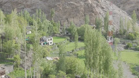 Drone Pull Out Shot Revealing a House Beneath Mountains with Lush Green Fields Stock-Footage 334398729