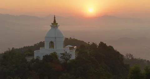 Drone pull in shot of World Peace Stupa with golden sunrise clouds, Pokhara Video stock 333284596