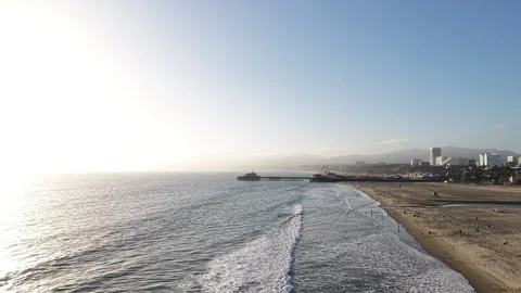Drone Pullback Along Santa Monica Beach with Waves, People and Pier in Distance Stock Footage 332326189