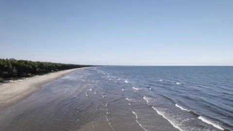 Drone pullback as long parallel lines of waves crash on sandy flats of Video stock 258640930