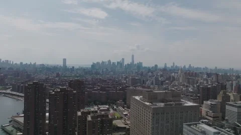 Drone pullback over East River shoreline with Manhattan in distance Video stock 333936309