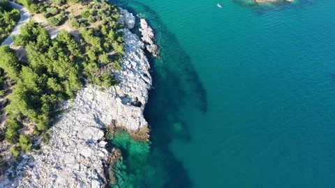 Drone Pullback Over Forested Rocks and Clear Blue Sea Stock Footage 340508943