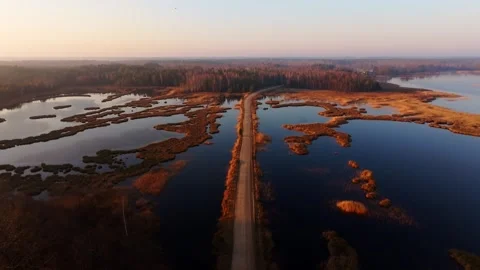 Drone Pullback Over Lake Kanieris Wetlands With Road At Spring Sunrise Latvia Stock Footage 334735940