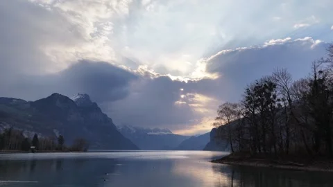 Drone pullback over Walensee at sunset with sun rays and alpine mountains Stock Footage 337788531