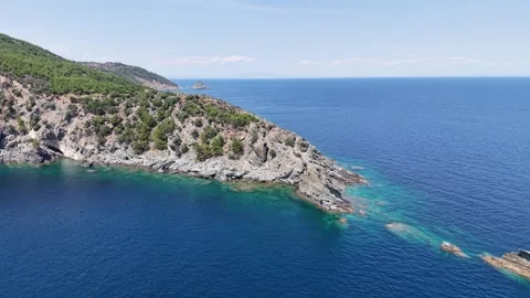 Drone Pullback Revealing Forested Headland and Clear Water Stock Footage 340508689