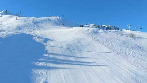 Drone pullback revealing ski slope, resort area and operating chairlift, ca.. Video stock 327353812