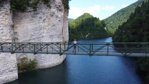 Drone pullback shot revealing a man on a suspension bridge over Senaiga Lake Vídeo Stock 331308798