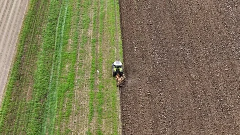 Drone Pulling Away from Tractor Plowing Agricultural Field Revealing Rich Soil Stock Footage 312773426