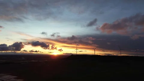 Drone Pulling Away from Wind Turbines as Solar Panels Appear at Sunset Stock Footage 325796988