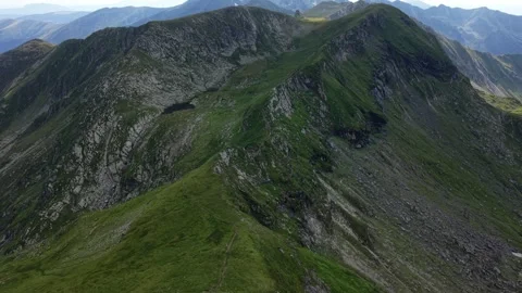 Drone pulling back above mountain hiking trail revealing alpine lake Stock Footage 340824640