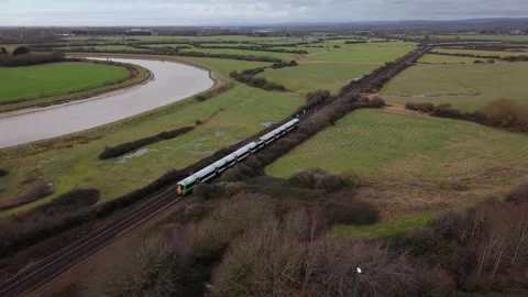 Drone pulling back from countryside over road bridge as train passes underne Stock Footage 327140267