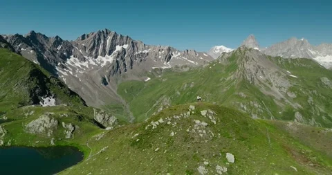 Drone Pulling Back from Hiking Couple Above Alpine Lake with Snowcapped Swiss Vídeo Stock 342345300