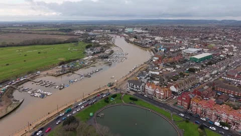 Drone pulling back over river mouth with moored boats and golf course in UK Stock Footage 327140207