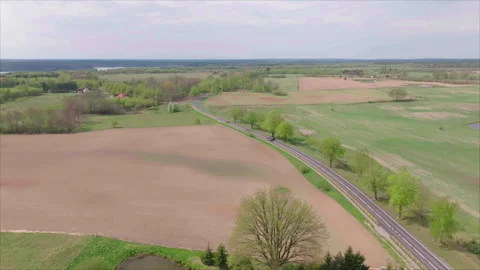 Drone pulling back to reveal Polish countryside with road, field, forest and vil Stock Footage 339170598