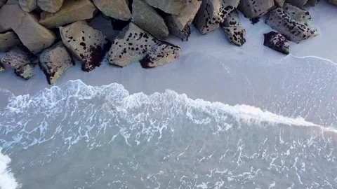 A drone pulling back from a rock breakwater on the coast, Coastal Engineering Stock Footage 316883642