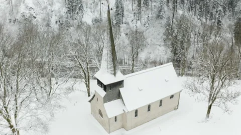 Drone pulling back from small church in snowy landscape revealing peaceful winte Video stock 332003625