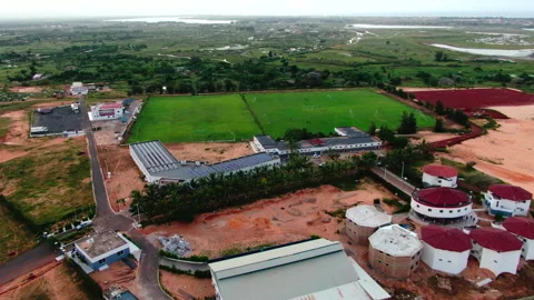 Drone pulling back from stadium in grassy plain with river, Senegal Stockbeeldmateriaal 331991529