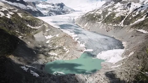 Drone pulling out footage of Rhone glacier melting into a turquoise lake Stock Footage 291280447