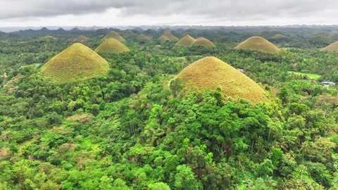 Drone pulls away revealing the iconic Chocolate Hills rising across the lush Stock Footage 313065075