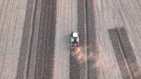 Drone pulls back and ascends, revealing a tractor with tilling machinery Stock Footage 321325661
