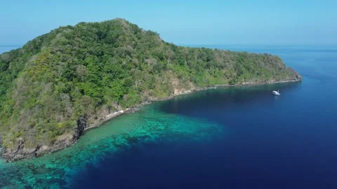 Drone pulls back and pans over reef with small boat Stock-Footage 327465718