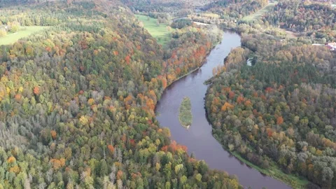 A drone pulls back over winding river bends set in a patchwork of autumn Video stock 313986718