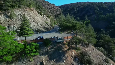 A drone pulls out from the pilot revealing a mountain road and forest. Stock Footage 247161406