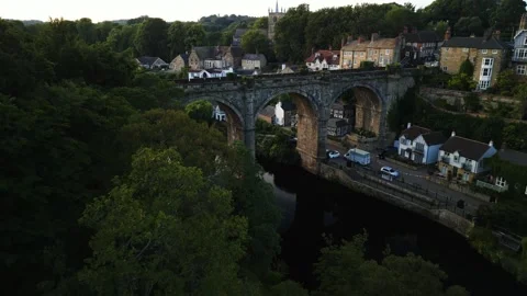 Drone pulls pack flying low over green trees overlooking the historic Stock Footage 321440211