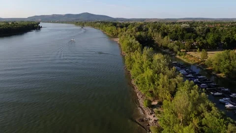Drone Push Over a River with Boats, Forest, and Distant Mountains Stock Footage 314077285