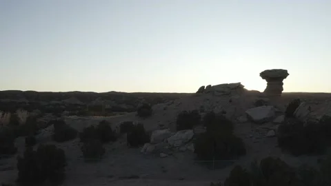 Drone push in reveals the sun behind a small desert rock formation Video stock 167665828