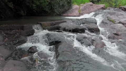 Drone Push In Shot of Small River Flowing Through Rocks in Tropical Forest Stock Footage 314667151