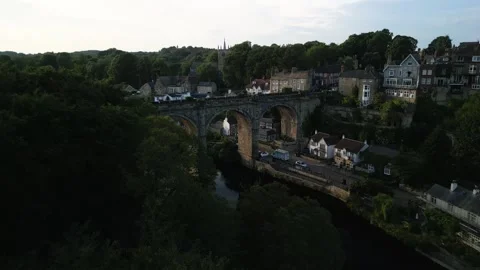 Drone push tilt over large bushy green trees to reveal large stone bridge Stock-Footage 321440217