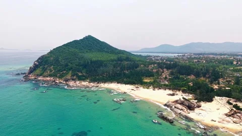 Drone push toward a lush green mountain beach and clear sea 4K Stock Footage 340069544