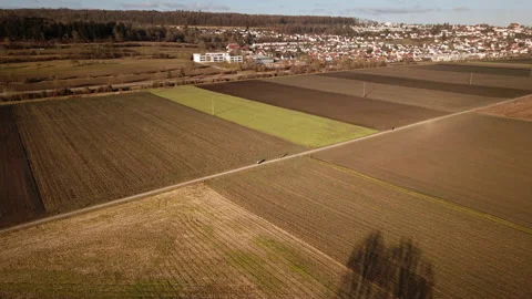 Drone pushes in over patchwork winter fields toward village Video stock 325179001
