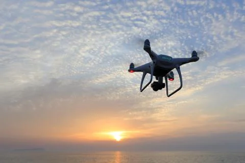 Drone quad copter with flying in the sunset sky Stock Photos