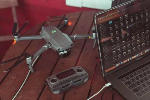 Drone quadcopter with a flight controller and notebook on the old wooden table. Stock Photos