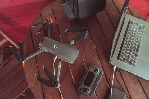 Drone quadcopter with a flight controller and notebook on the old wooden table. Stock Photos