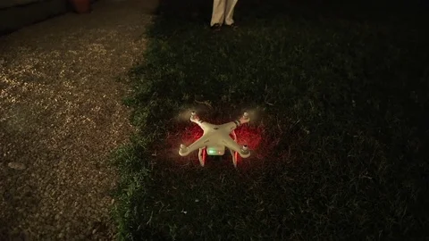 Drone quadcopter taking off from ground to night sky with operator controlling Stock Footage 70682982