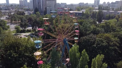 A drone quickly flies around a spinning multicolored Ferris wheel in a park Stock Footage 145058317