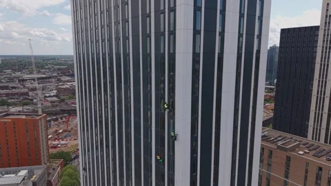 Drone reveal of rope access workers cleaning Birmingham skyscraper windows Stock-Footage 334691524