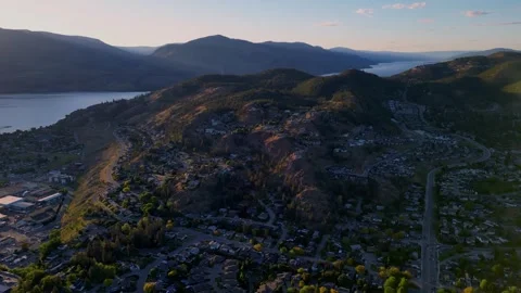 Drone reveals Knox Mountain rising above Kelowna at sunset with warm orange Stock Footage 336900545