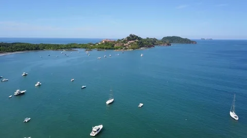 Drone reverse flight over Playa Flamingo bay filled with boats Stock Footage 90926141