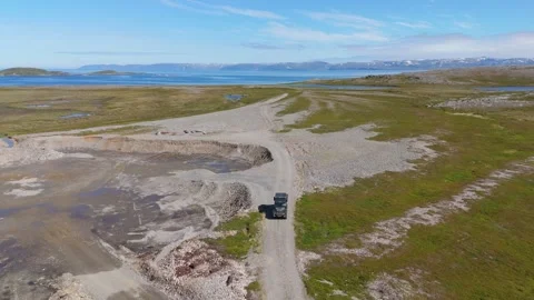 Drone reverse move above Land Rover on gravel track at Nordkapp fjord, Norway 動画素材 337640889