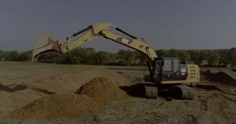 Drone Revolves around Excavator Digging Dirt in Field Stock Footage 81755983