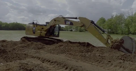 Drone Revolves around Excavator Dumping Dirt in a Field Stock Footage 81755933