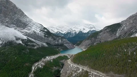 Drone rises above dense snowy forest on the slopes of massive mountains Video stock 137512951